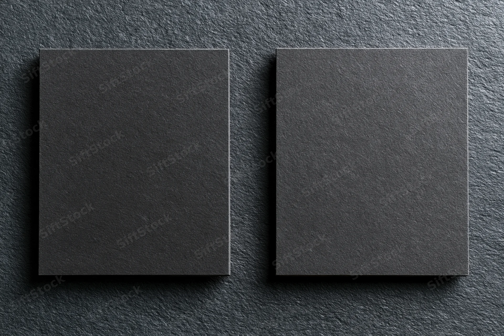 Two blank dark grey business cards lying flat side by side on textured surface
