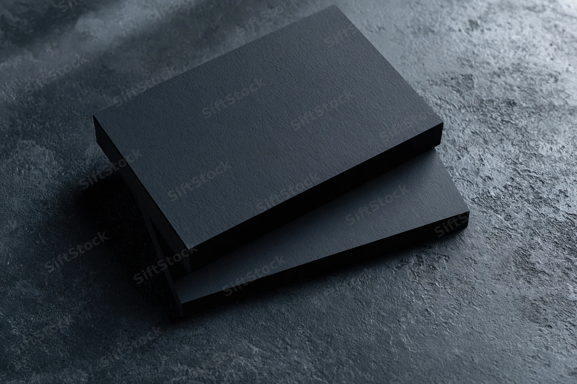 Two blank matte black business cards stacked slightly offset on a dark textured surface