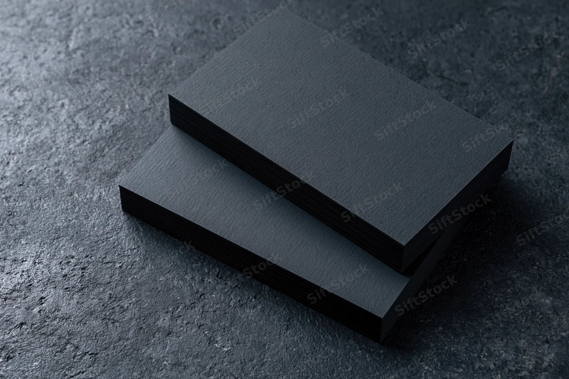 Two blank matte black business cards stacked offset on a dark textured surface