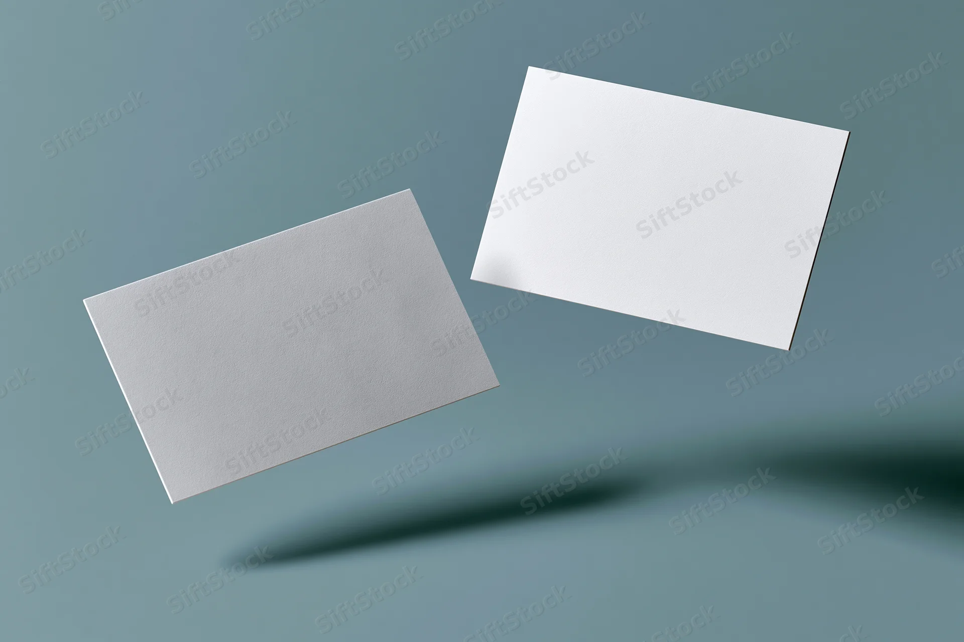 Two blank white business cards floating at slight angles against a blue-gray gradient background