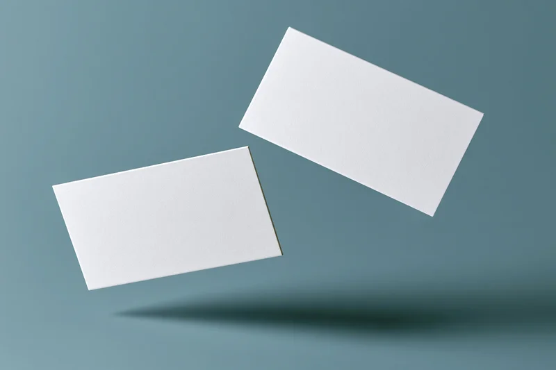 Two blank white business cards floating against a gradient blue background with soft shadow