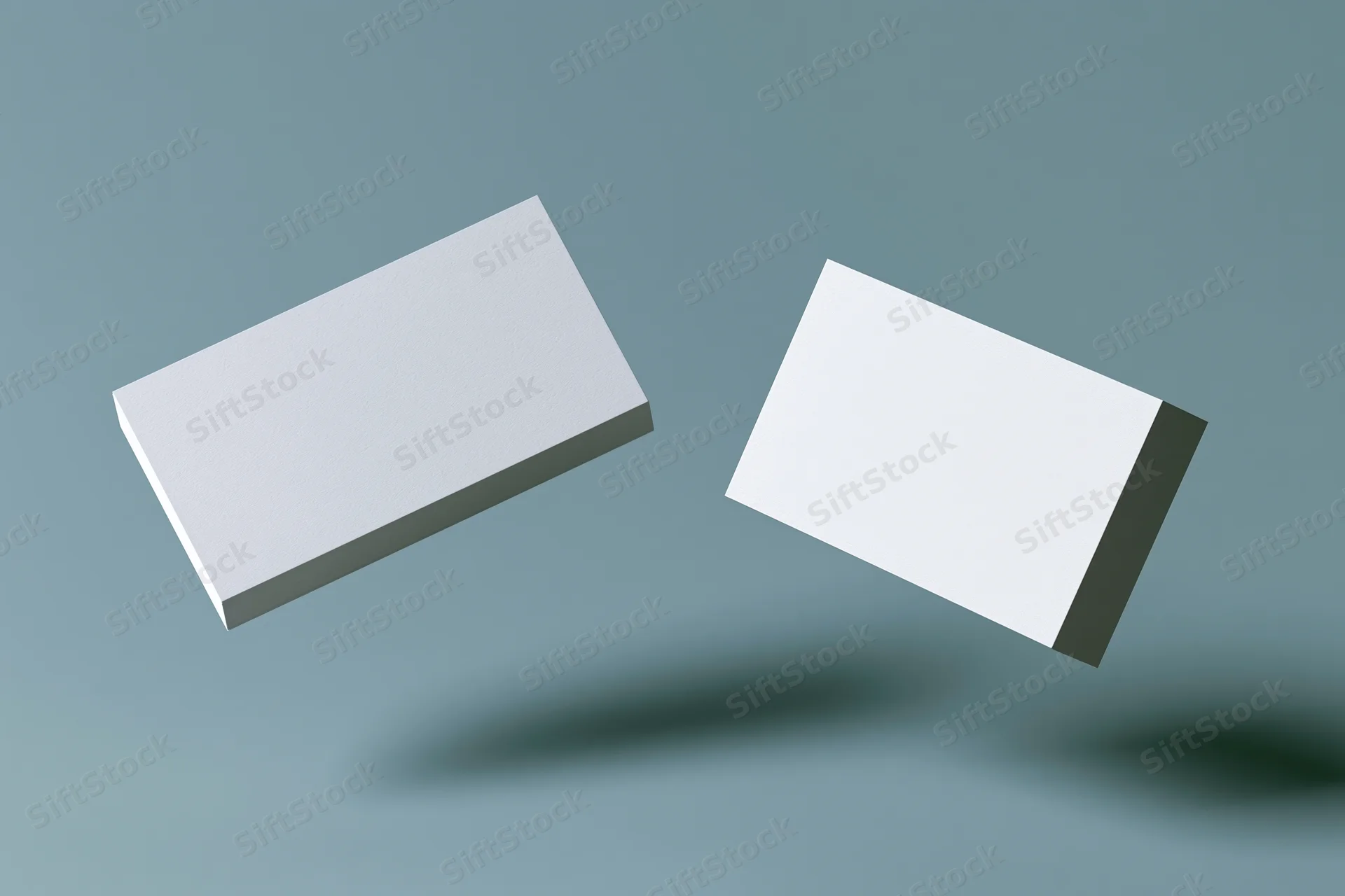 Two blank white business cards floating at slight angles against a muted blue background with soft shadows