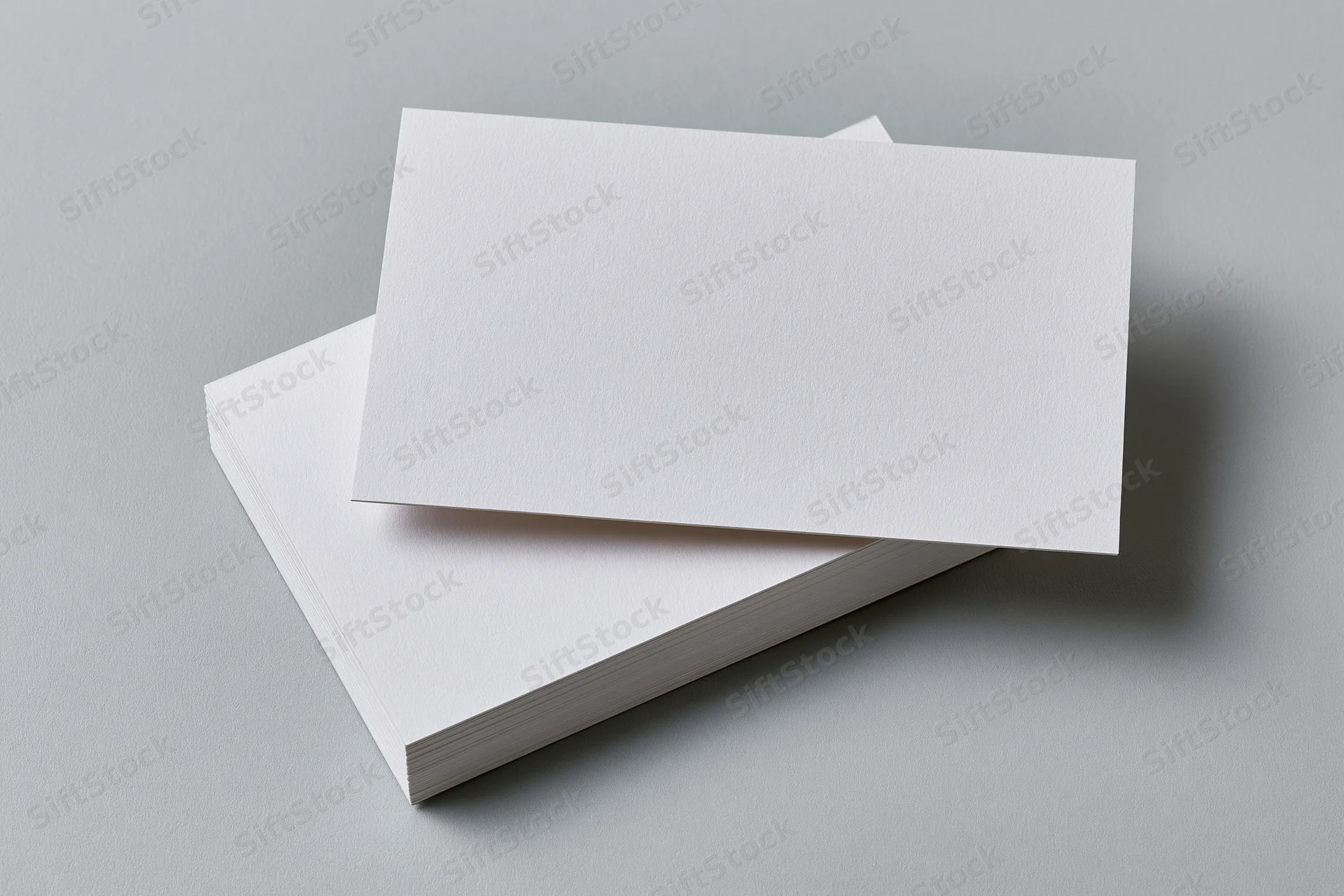 Blank white business cards stacked at slight angle on gray surface