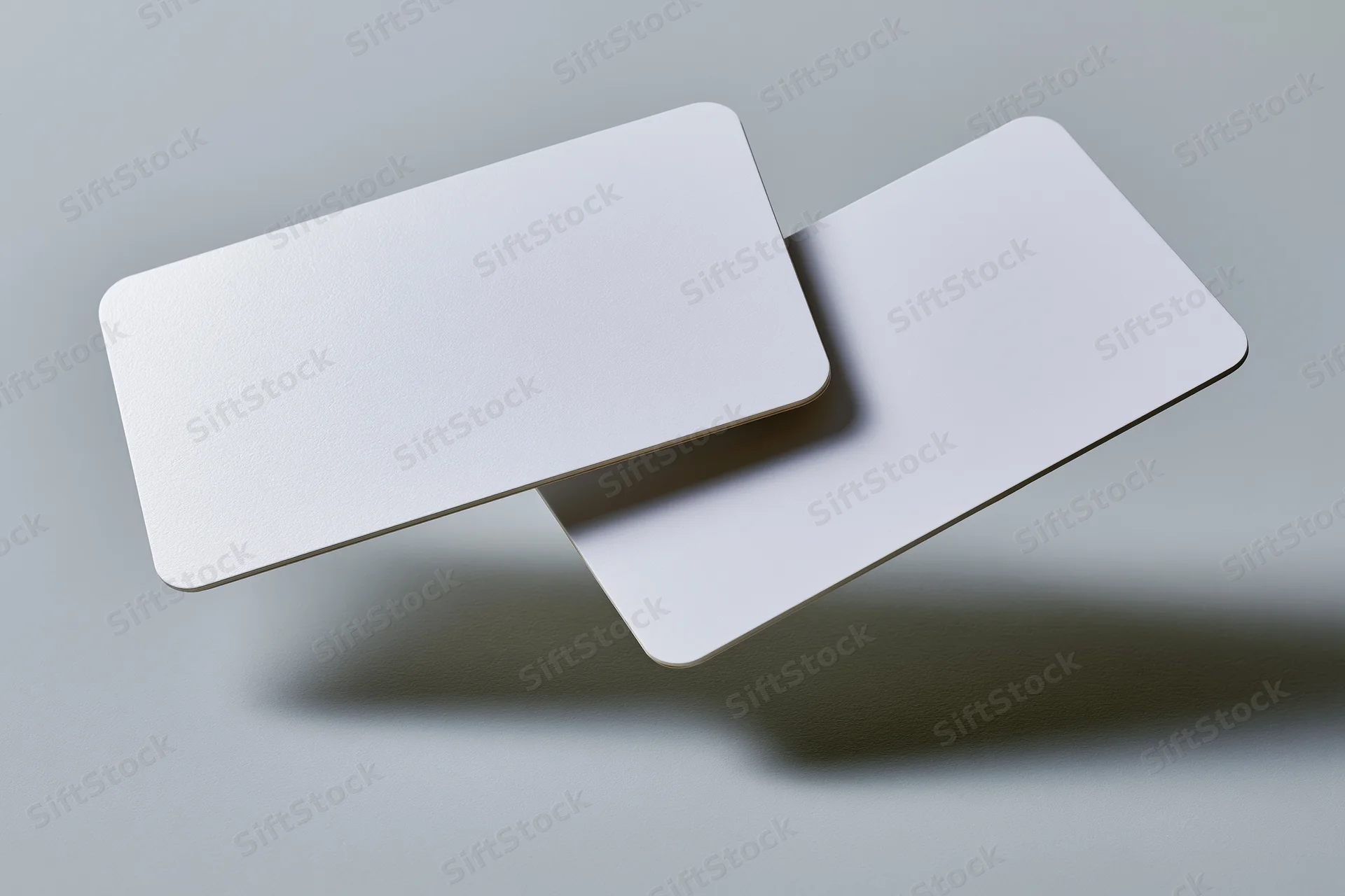 Two blank white business cards with rounded corners floating above a gray surface