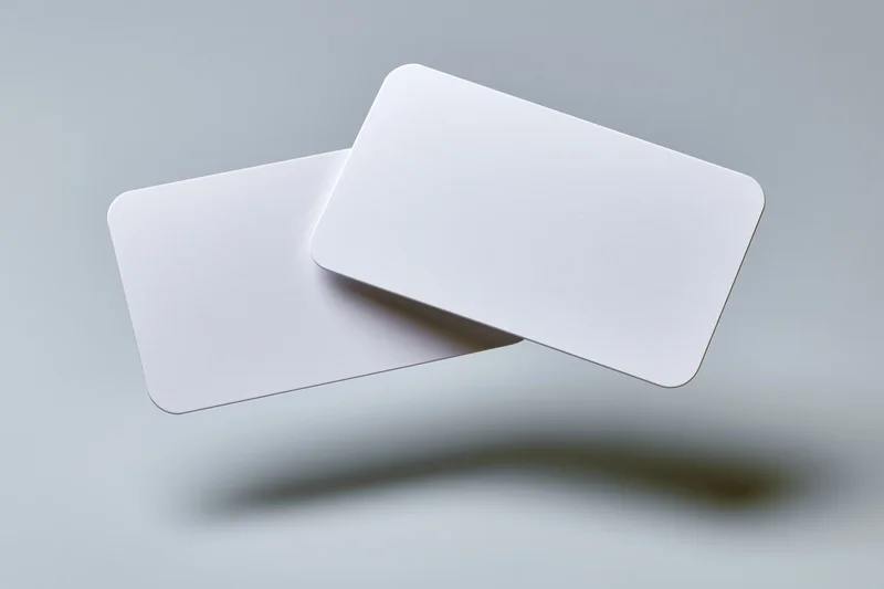 Two blank white business cards with rounded corners floating against a gray background