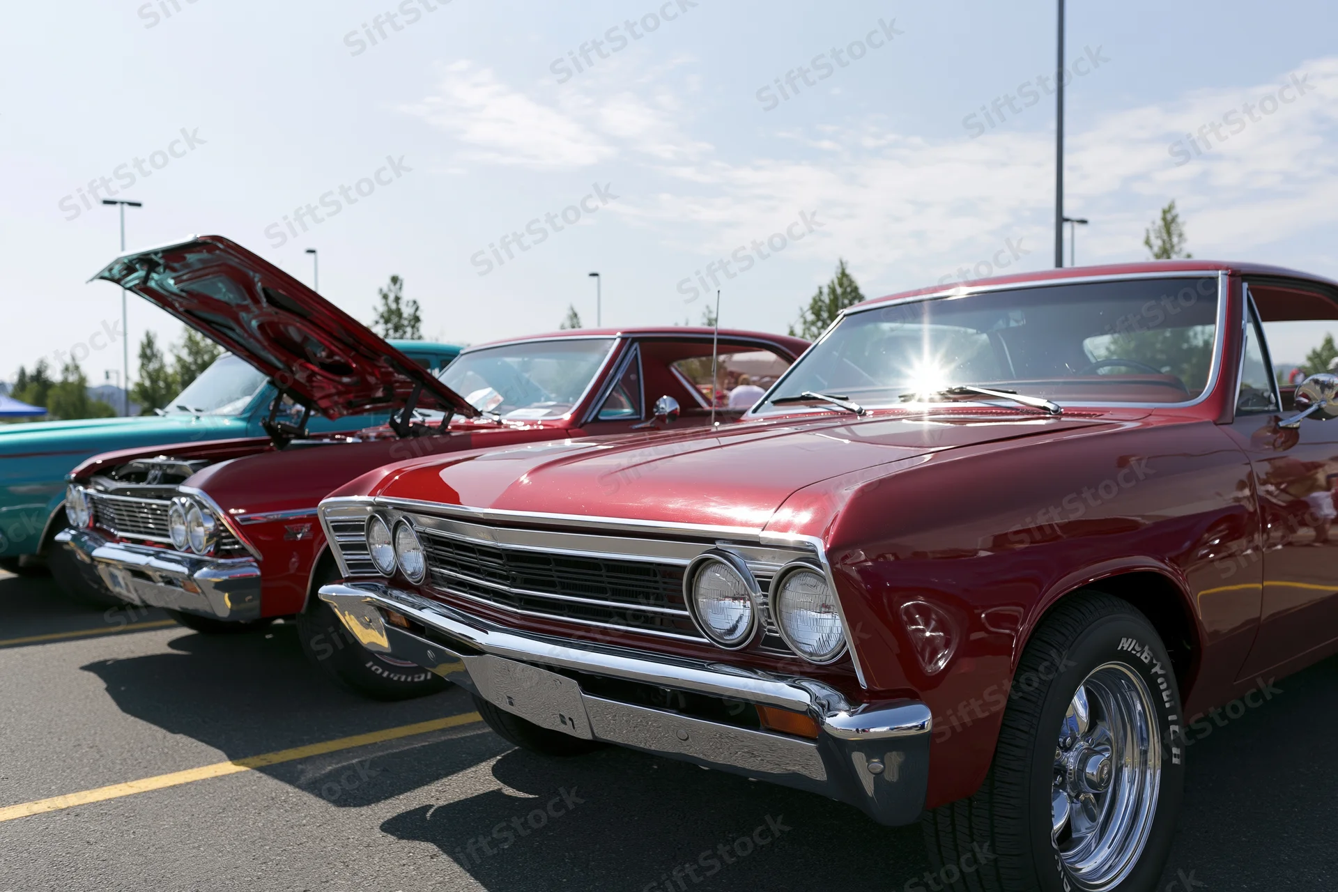 Classic american muscle cars parked in a row at an outdoor car show with hoods open under bright sunlight