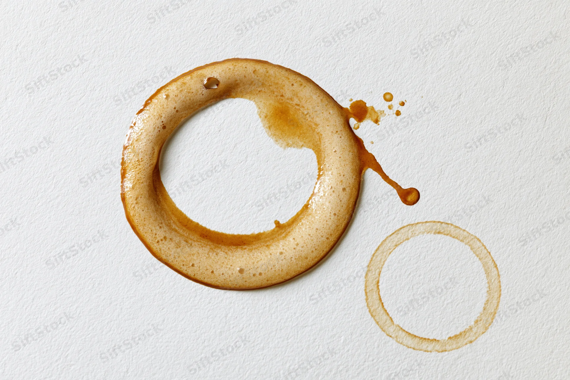 Coffee ring stains on white paper surface with foam and drip marks