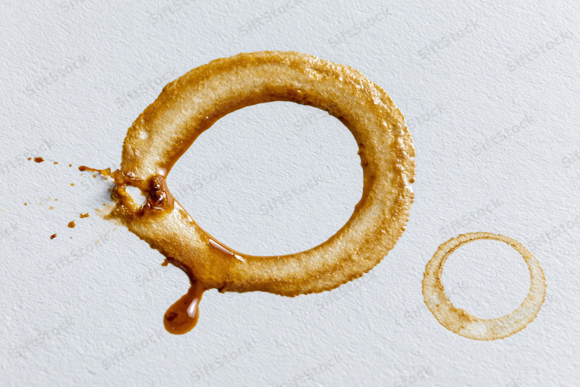 Coffee ring stains on white surface with drip and splash detail
