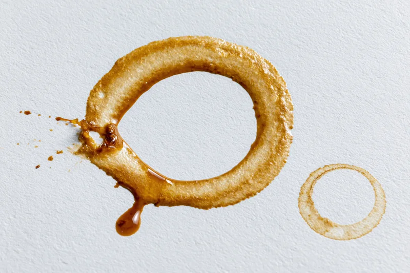 Coffee ring stains on white surface with drip and splash detail