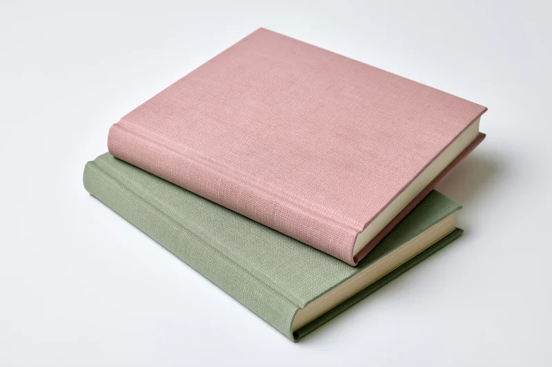 Two hardcover books stacked at an angle on a white surface