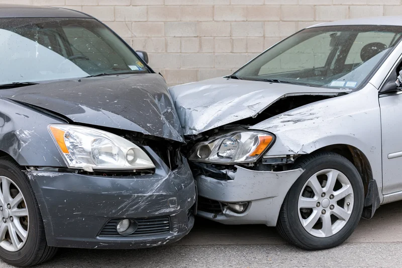 Two damaged cars collided front-end in a parking lot