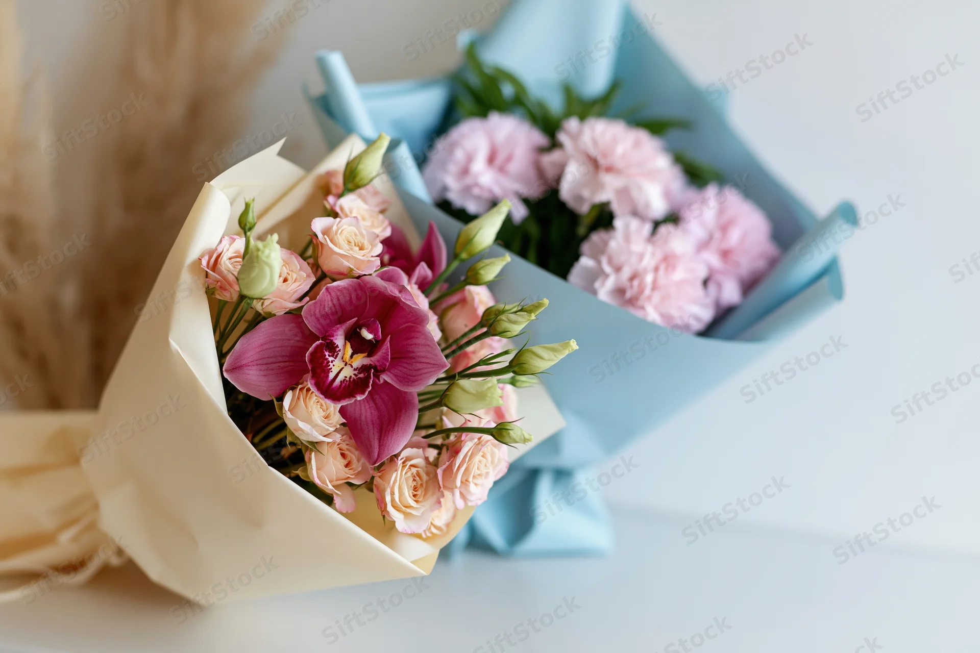 Two wrapped flower bouquets arranged side by side on a light surface