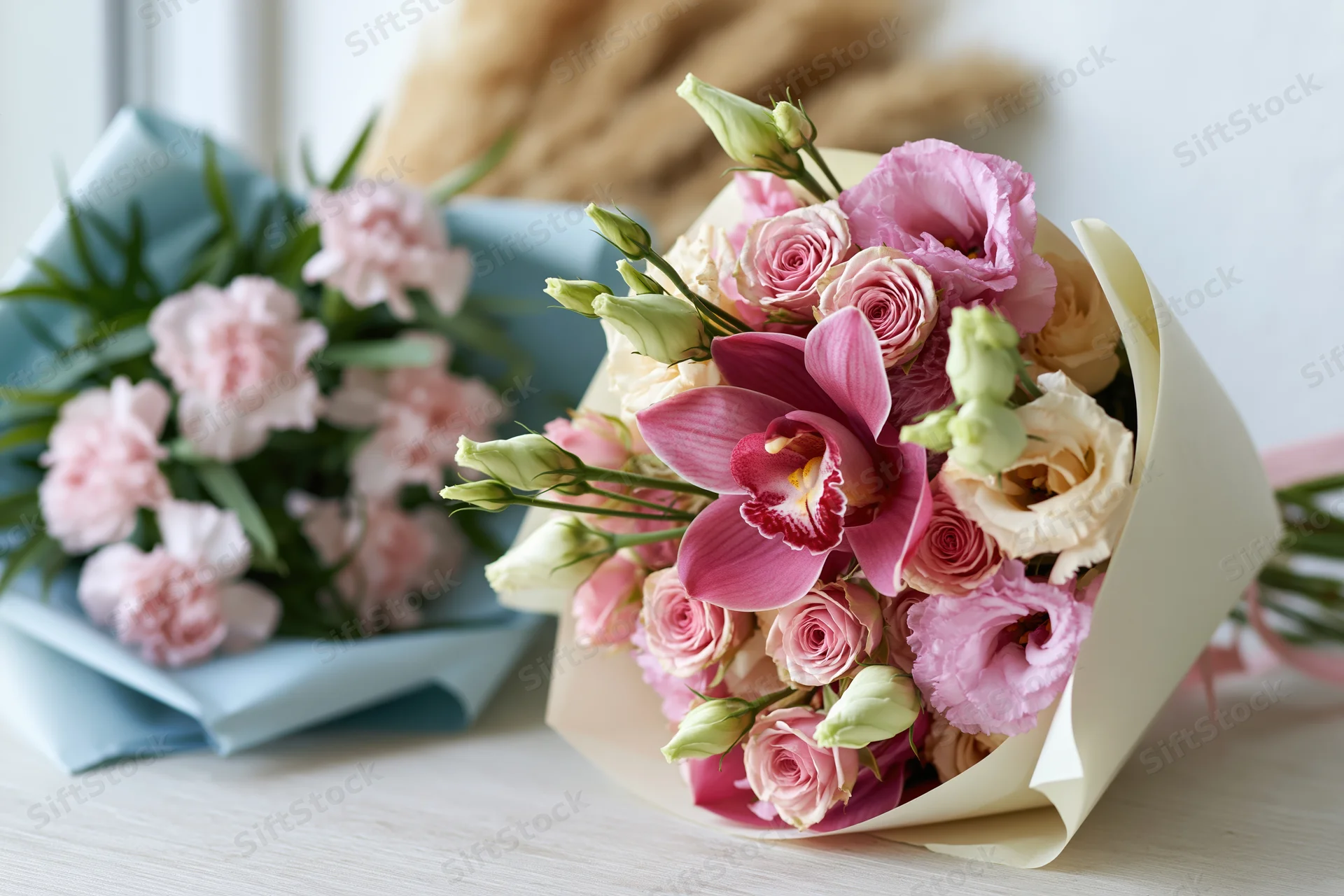 Two wrapped flower bouquets arranged side by side on a light wooden table