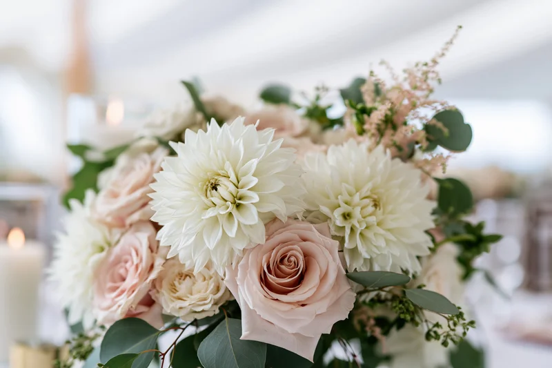 Wedding centerpiece with white dahlias and blush roses on a table