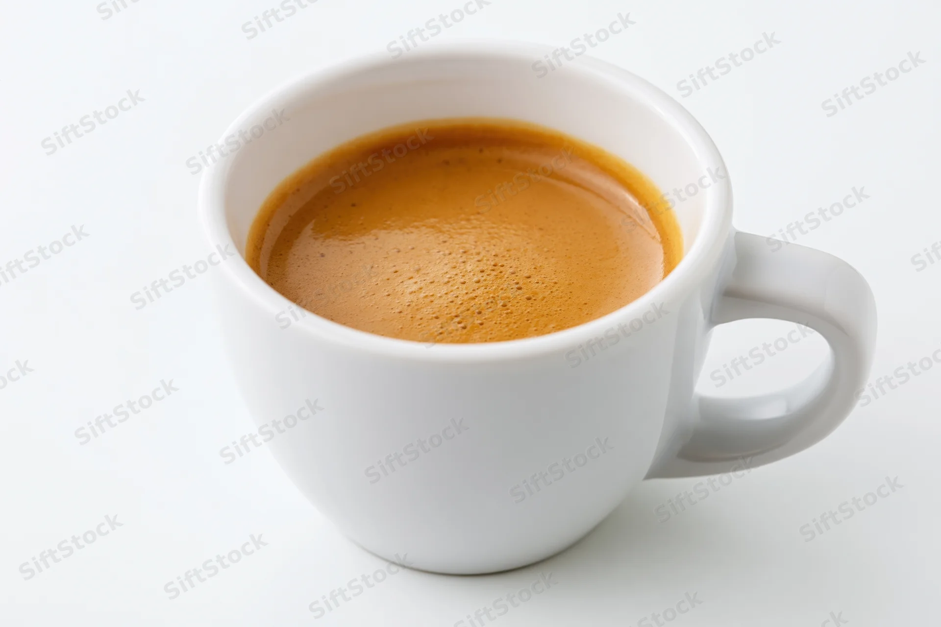 White ceramic cup filled with espresso showing crema on plain white surface