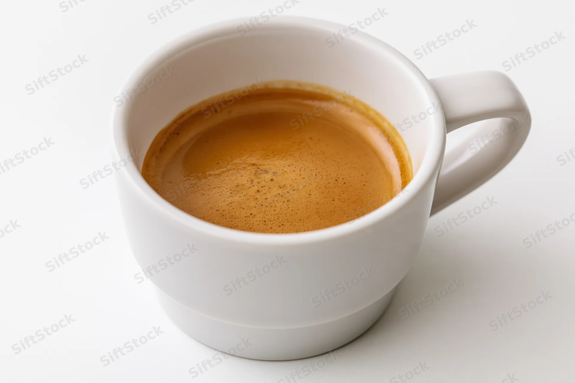 White ceramic cup filled with espresso showing crema on plain white background