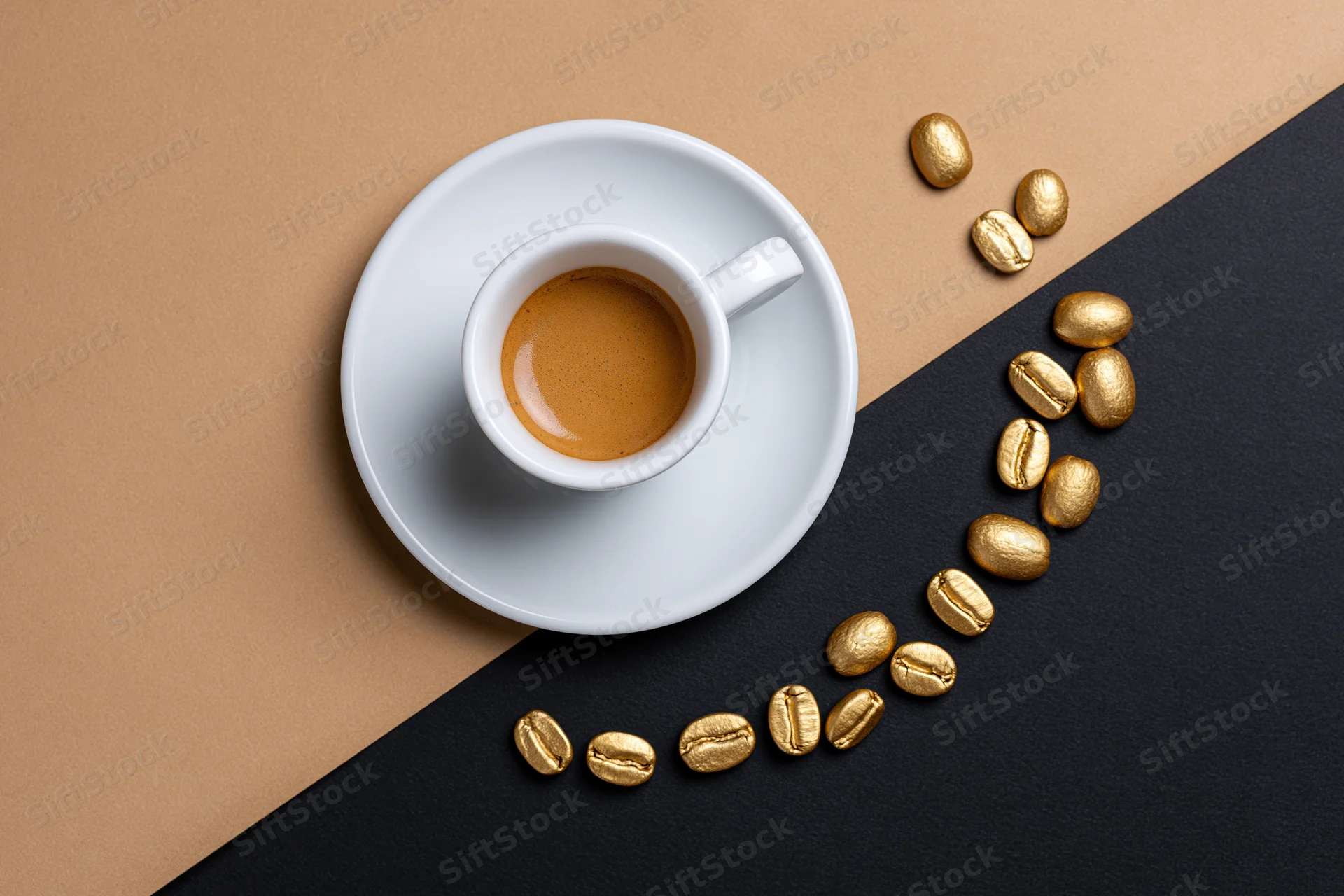 White espresso cup with crema on saucer surrounded by golden coffee beans on two-toned surface