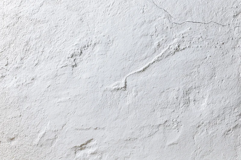 White plaster wall with cracks and rough texture filling the frame