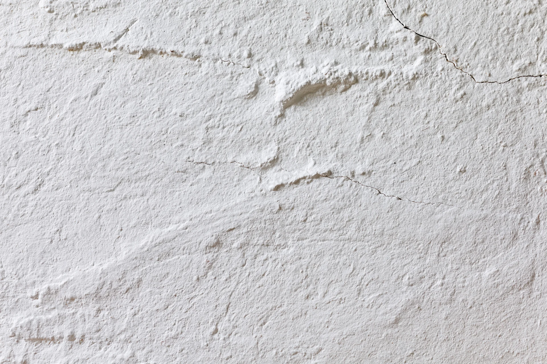 White plaster wall with cracks and texture filling the frame