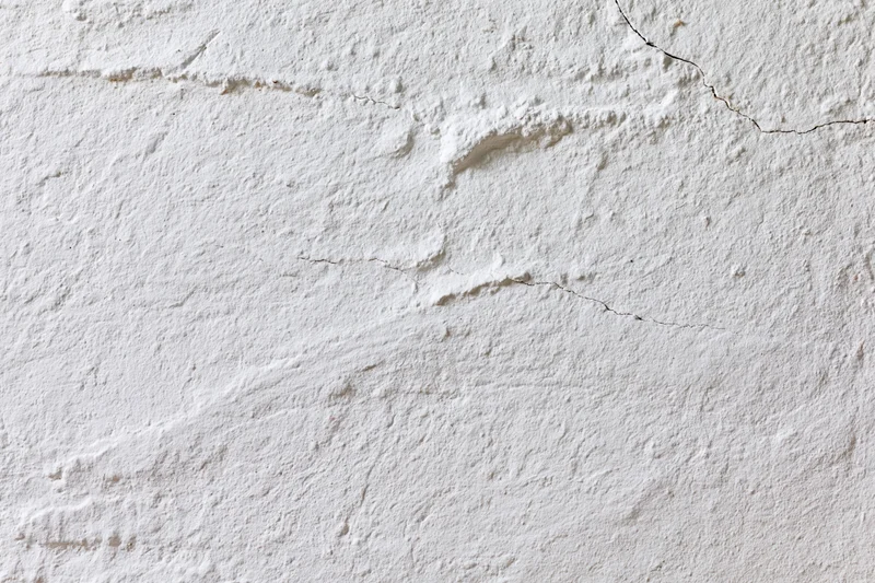 White plaster wall with cracks and texture filling the frame