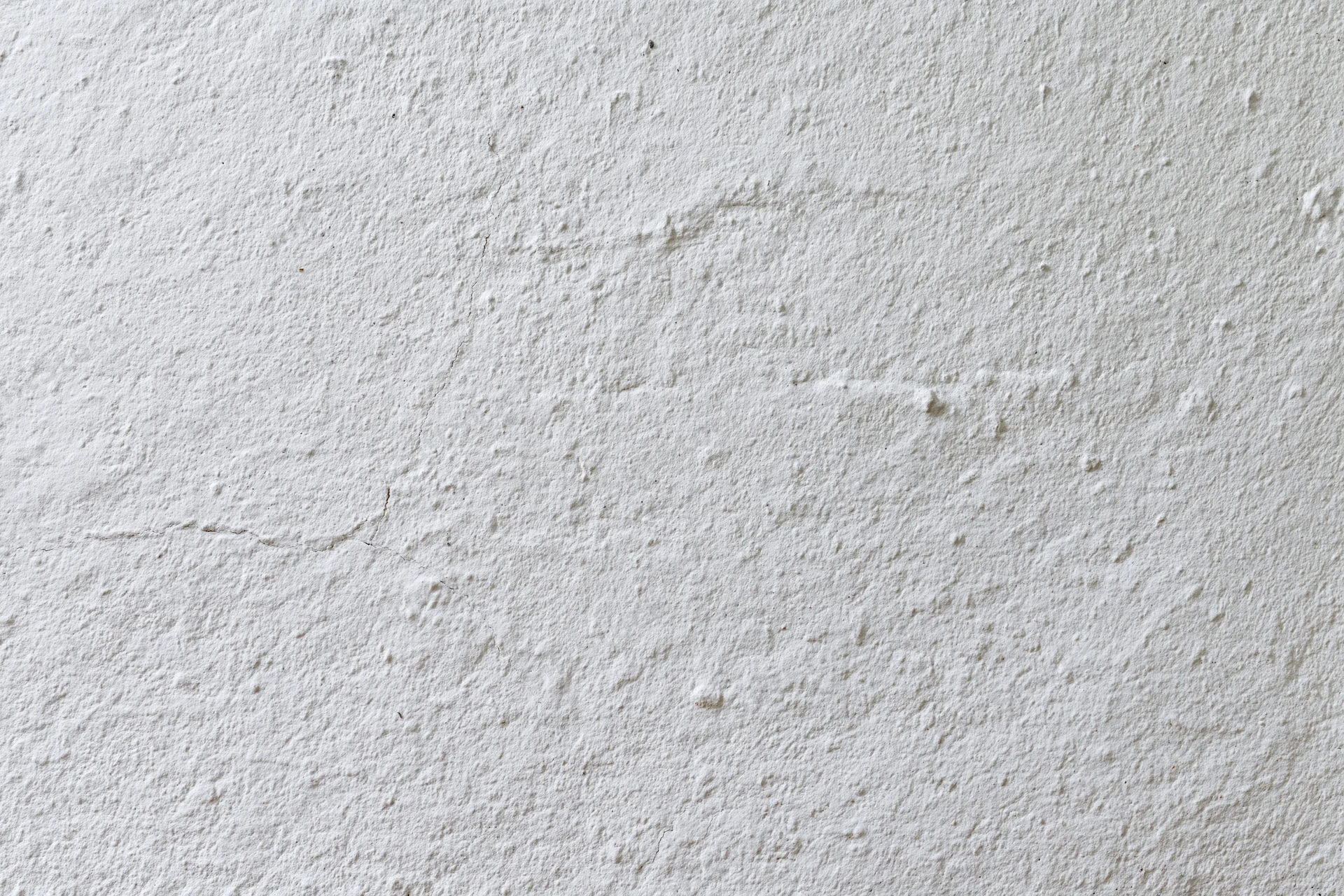 White plaster wall surface with rough texture and minor cracks filling the frame
