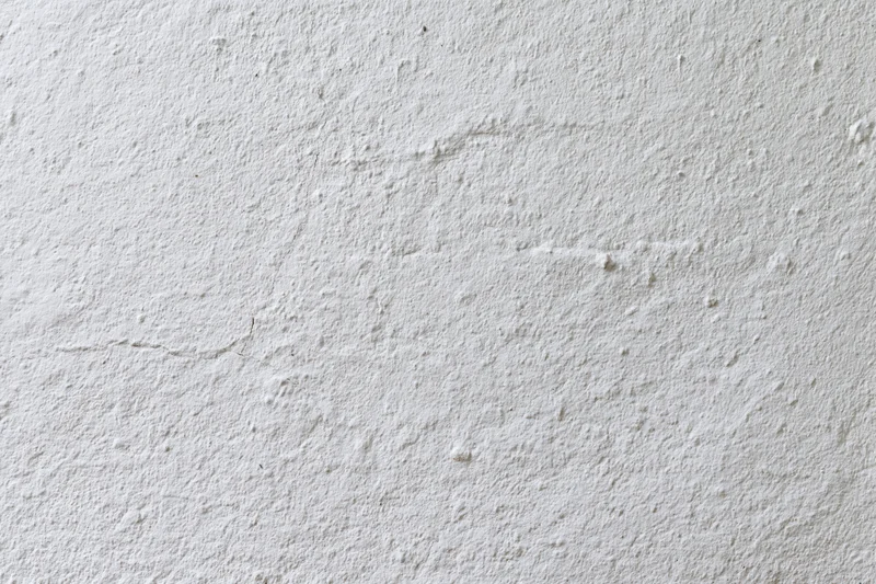 White plaster wall surface with rough texture and minor cracks filling the frame