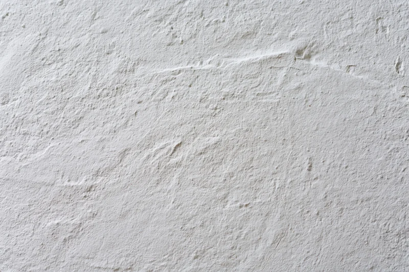Close-up of a white plastered wall surface with rough texture and small cracks