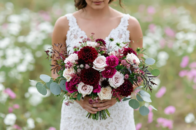 Bride holding a large loose floral bouquet in a garden field