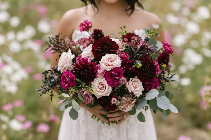 Bride holding a large loose floral bouquet in a garden field