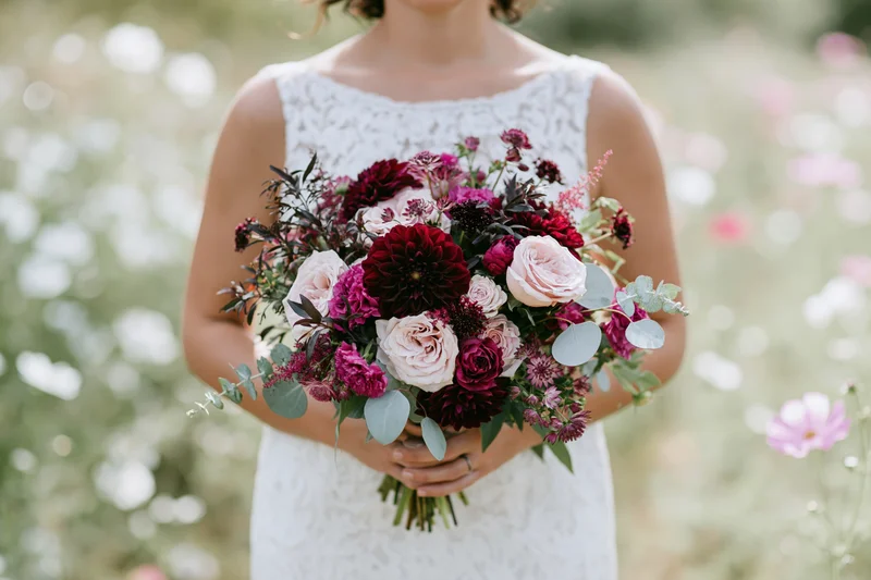 Bride holding a large loose floral bouquet in a garden setting