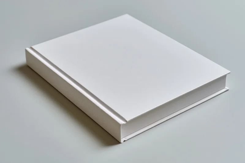 Blank white hardcover book lying flat on a neutral surface with copyspace