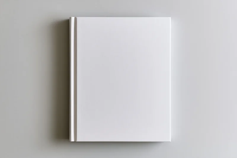 Blank white hardcover book lying flat on a gray surface