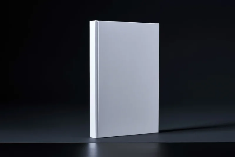Blank white hardcover book standing upright on dark matte surface with copyspace