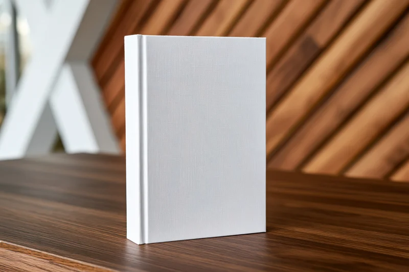 Blank white hardcover book standing upright on dark walnut table