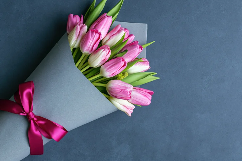 Bouquet of pink and white tulips wrapped in grey matte paper
