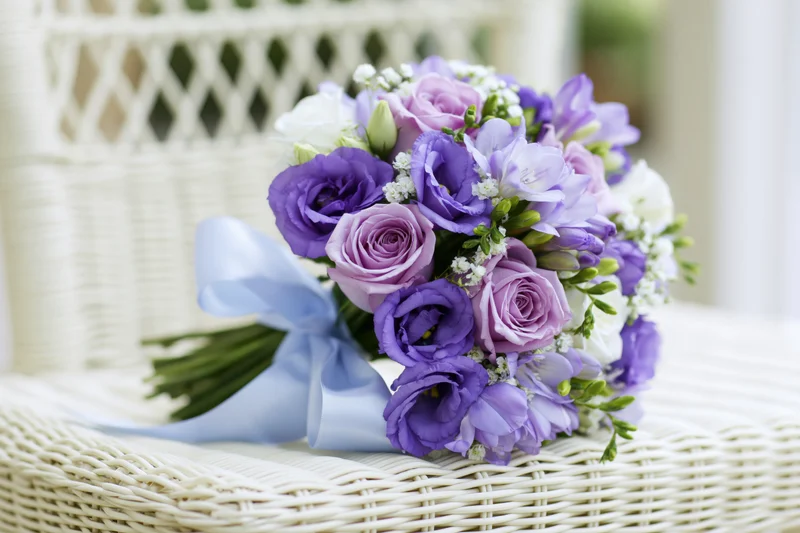 Bridal bouquet of purple roses and lavender lisianthus resting on a wicker basket