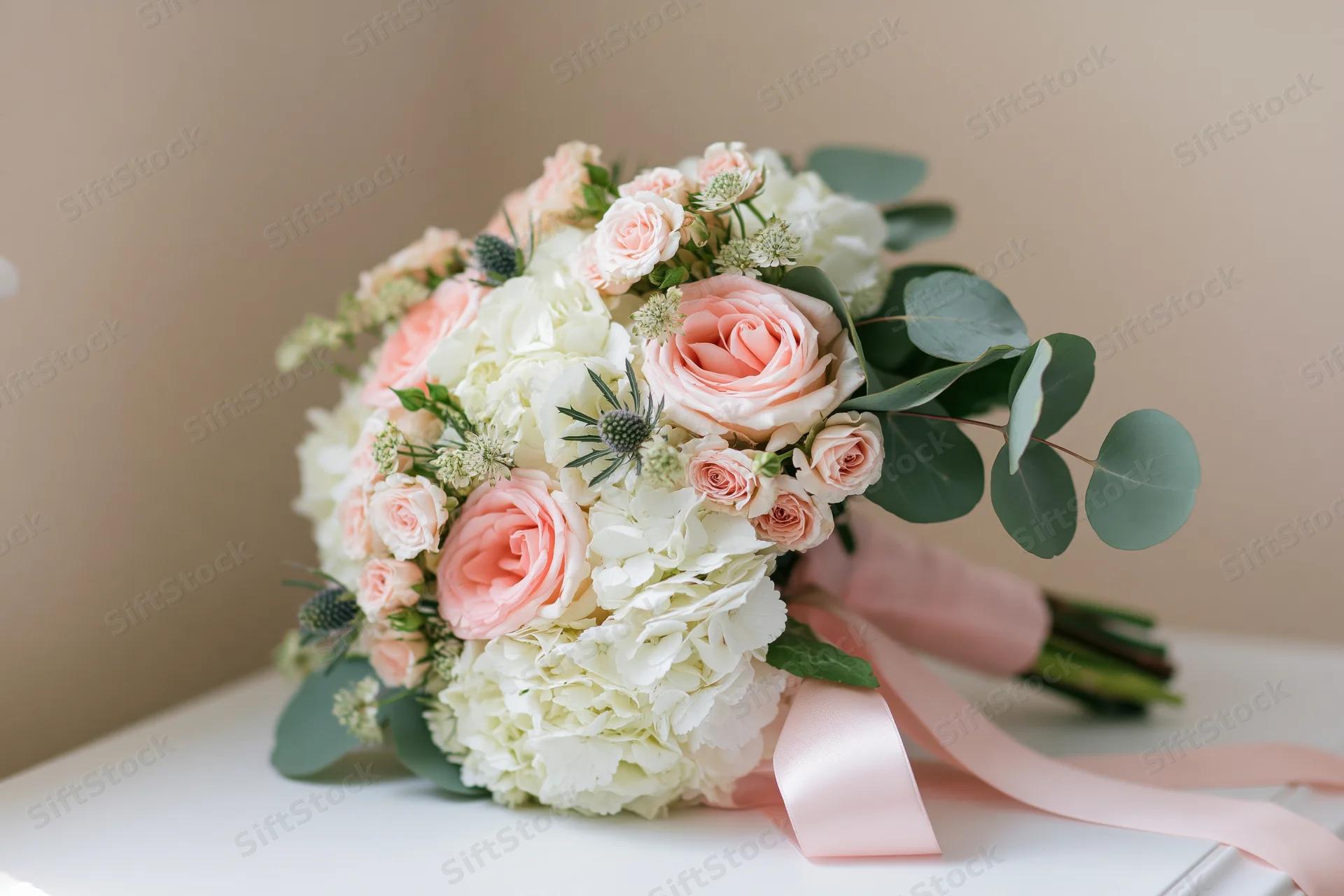 Bridal bouquet with pink roses and white hydrangeas on a white surface