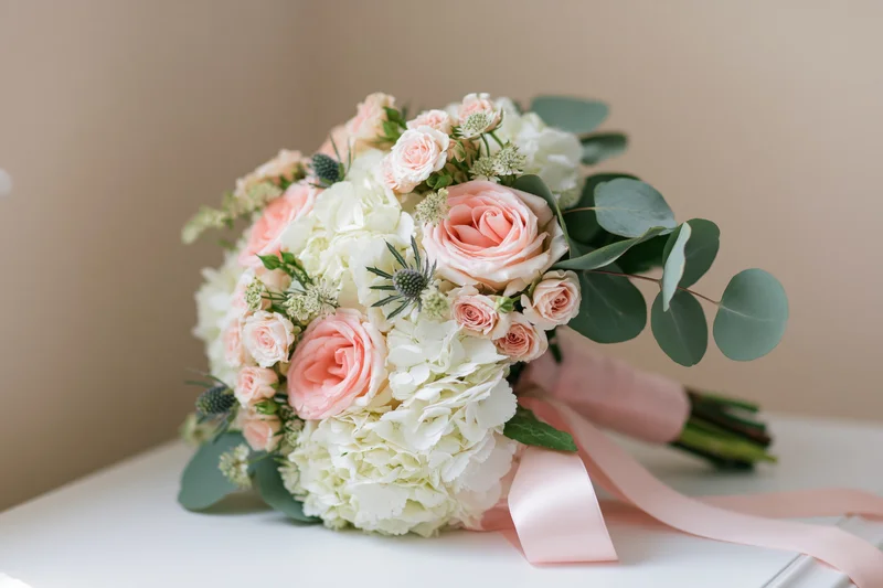Bridal bouquet with pink roses and white hydrangeas on a white surface