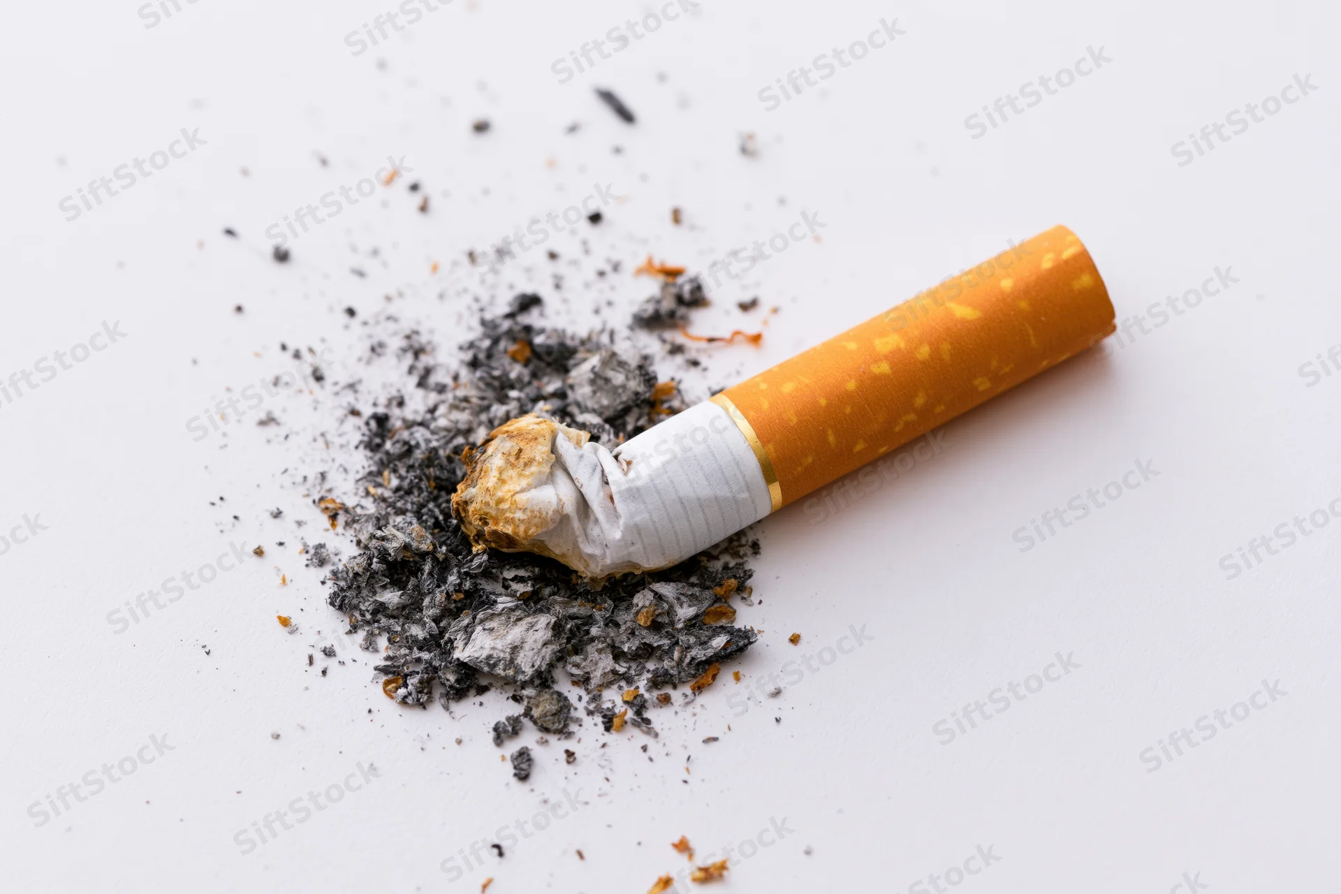 Crushed cigarette butt with ash on white surface
