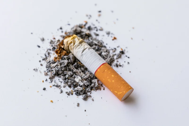 Crushed cigarette butt with ash on a white surface