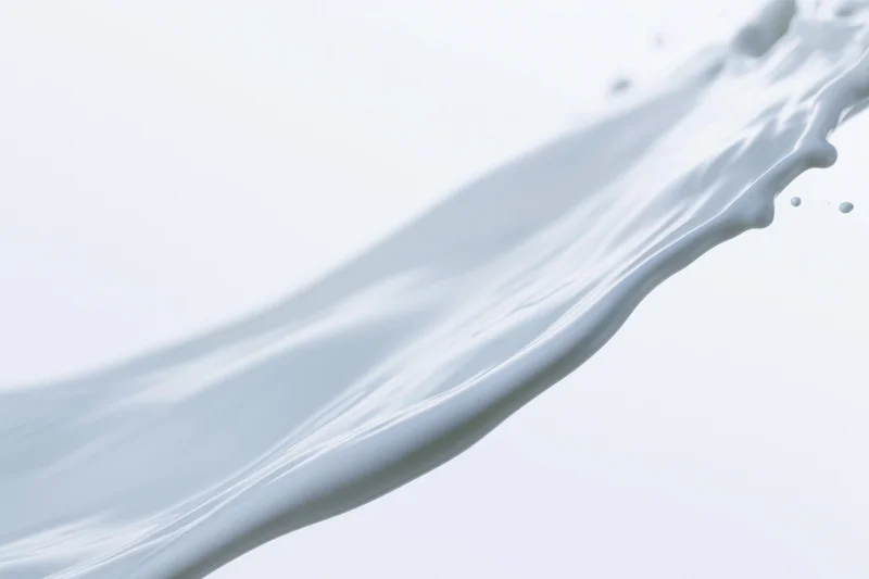 Flowing wave of white milk mid-splash captured in motion against a plain white background