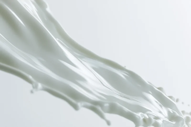 Flowing wave of white milk mid-splash against plain background