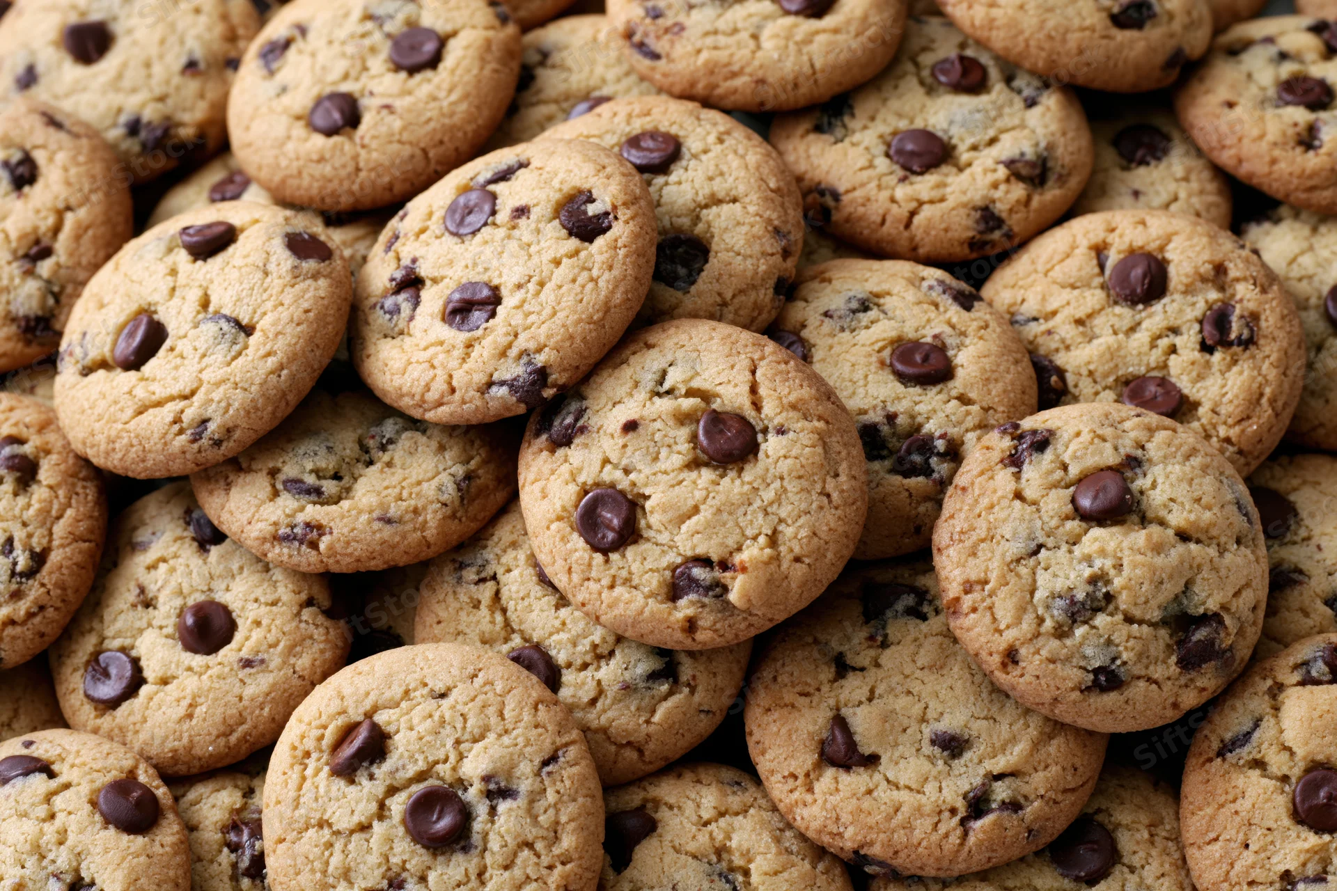 A pile of freshly baked chocolate chip cookies stacked closeup