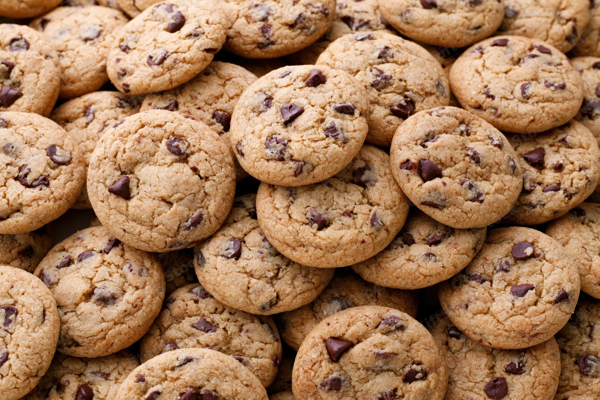 A pile of freshly baked chocolate chip cookies stacked closely together