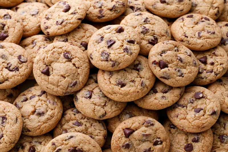 A pile of freshly baked chocolate chip cookies stacked closely together
