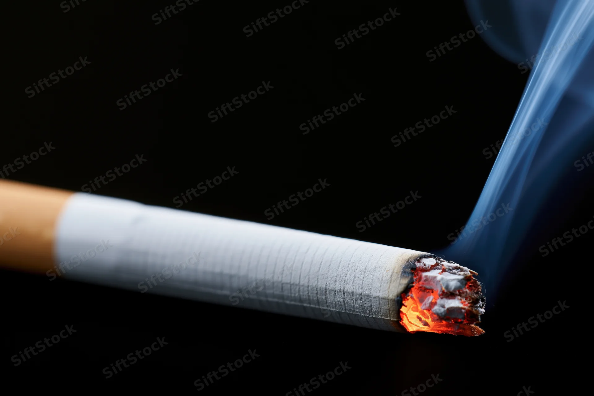 Lit cigarette burning with glowing ember and rising smoke against black background