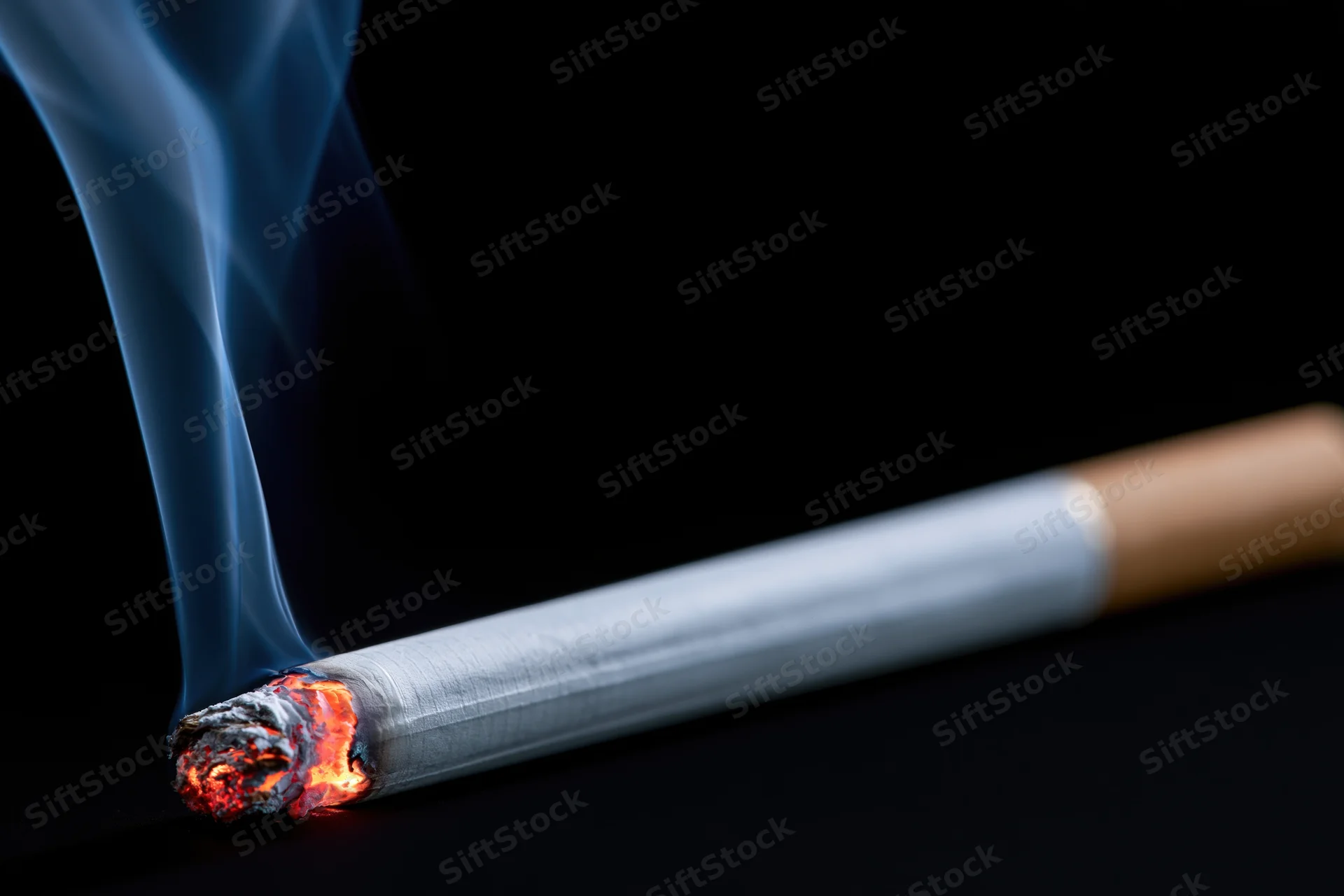 Lit cigarette burning horizontally against black background with rising smoke and glowing ember