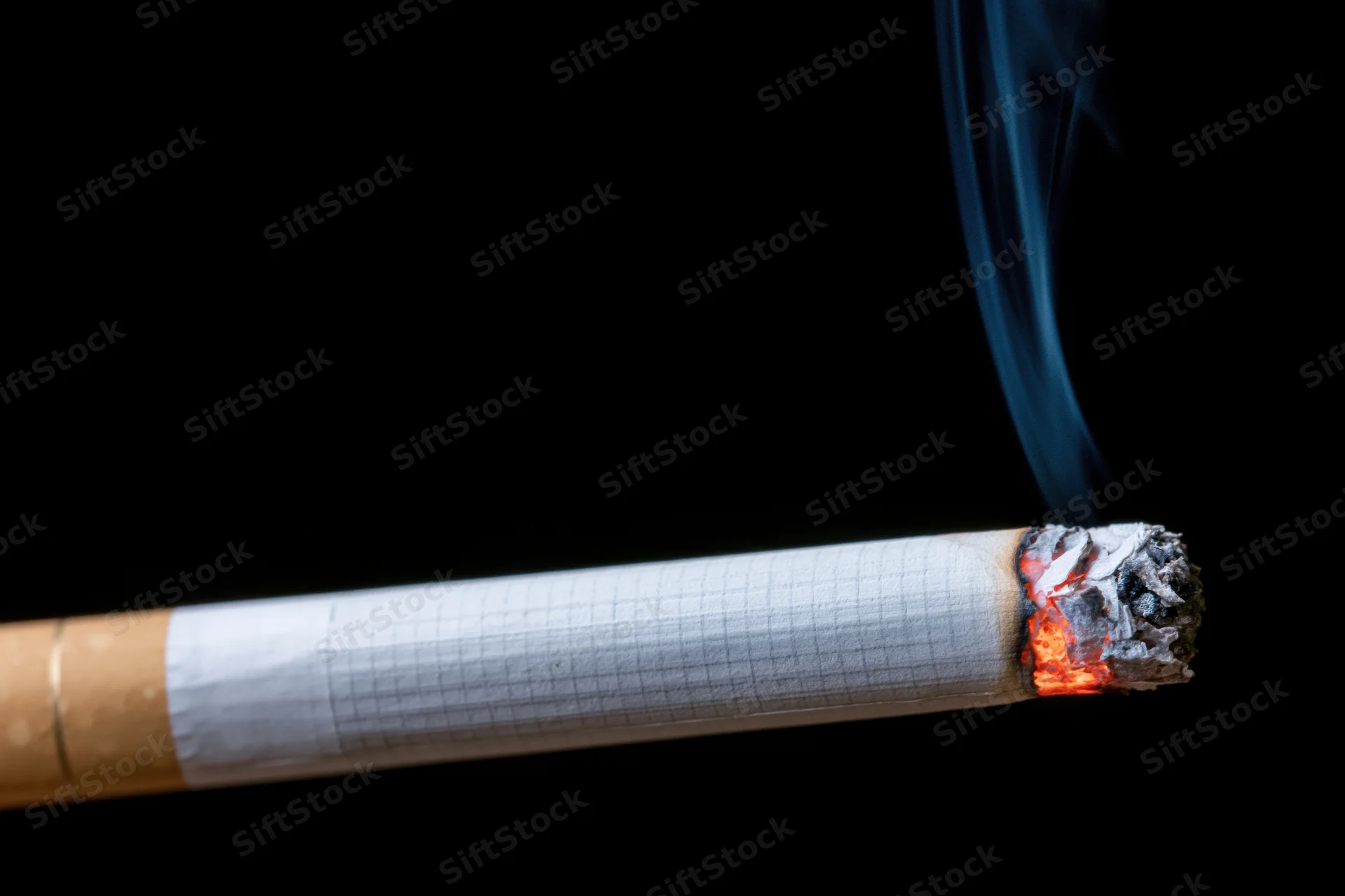 Lit cigarette burning horizontally against black background with rising smoke and glowing ember
