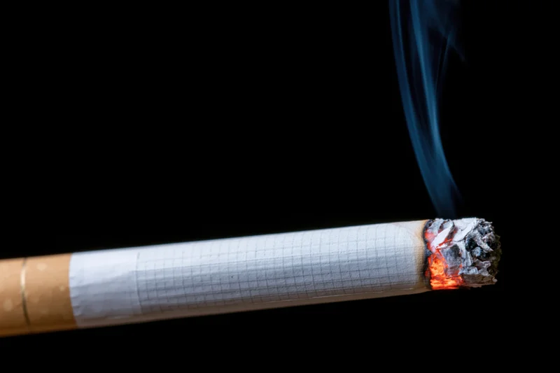 Lit cigarette resting horizontally against a pure black