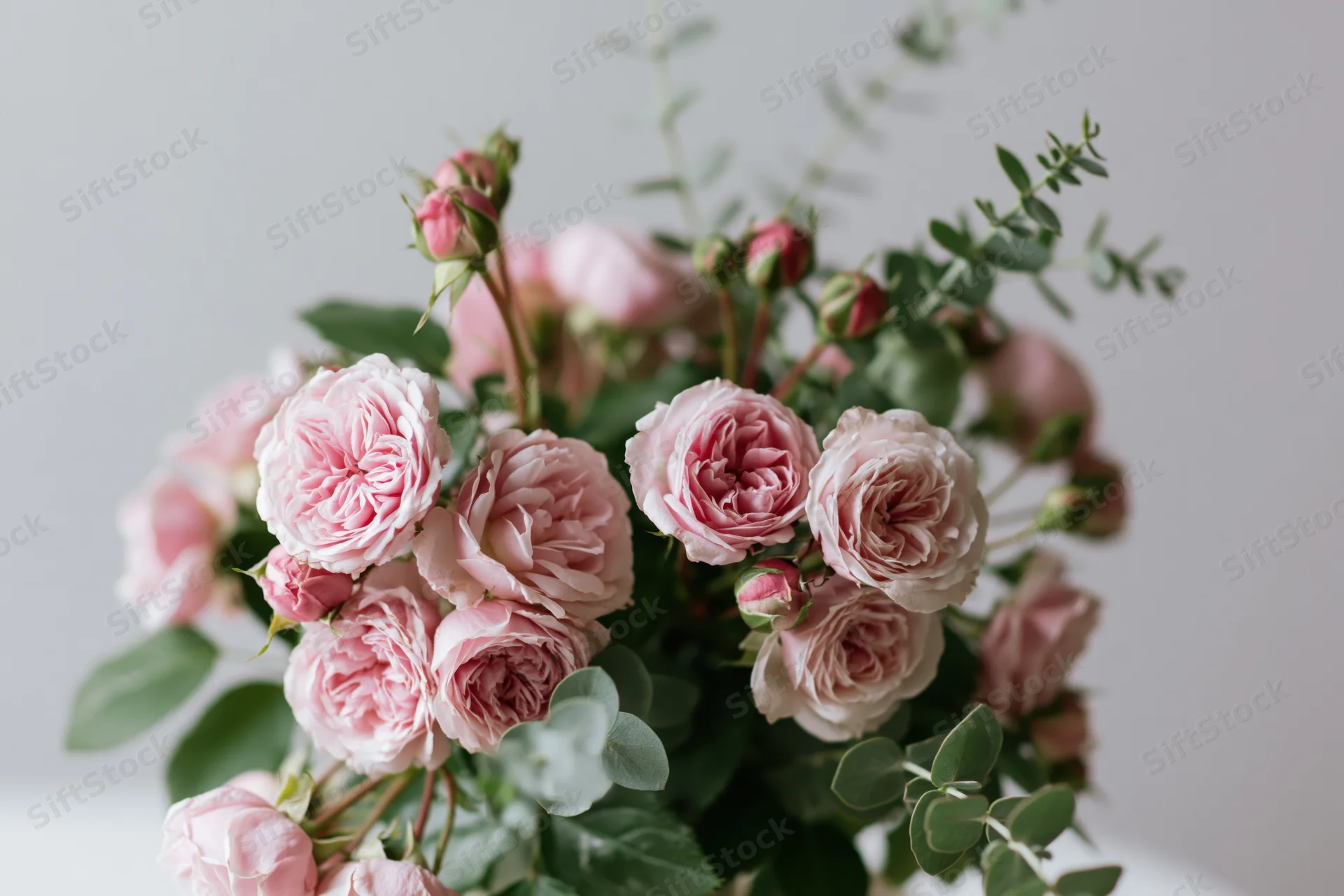 Loose bouquet of pink garden roses with eucalyptus foliage arranged in a soft floral display